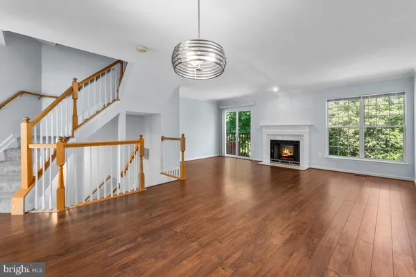 a view of an empty room with wooden floor fireplace and a window