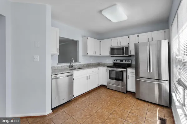 a kitchen with granite countertop a refrigerator stove and microwave