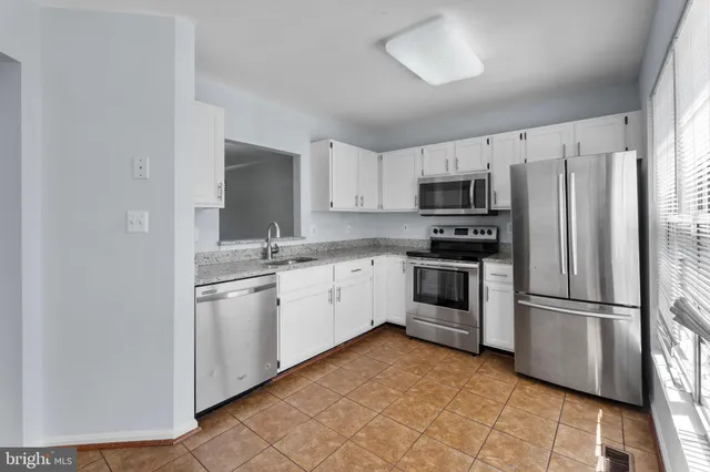 a kitchen with granite countertop a refrigerator stove and microwave