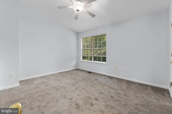 an empty room with a chandelier fan and windows