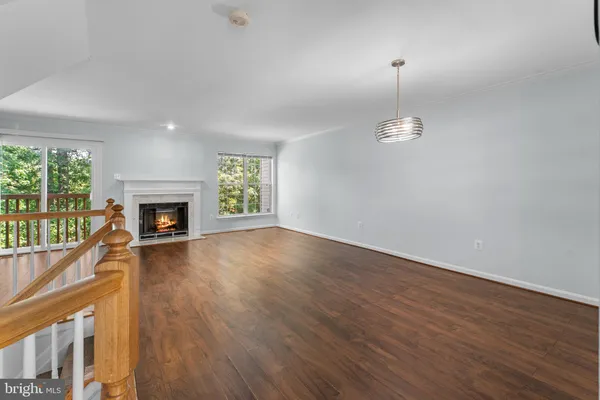 an empty room with wooden floor fireplace and windows