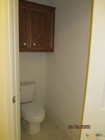 a white toilet sitting next to a wooden cabinet