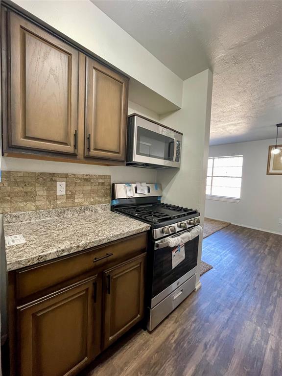 3543 Terrell Street Dallas, TX 75223 - Photo 11 of 26 a kitchen with granite countertop wooden cabinets stove and microwave