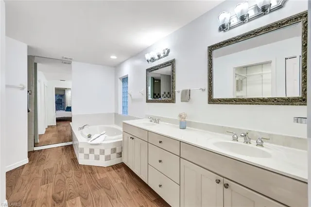 a spacious bathroom with double vanity a mirror and bathtub