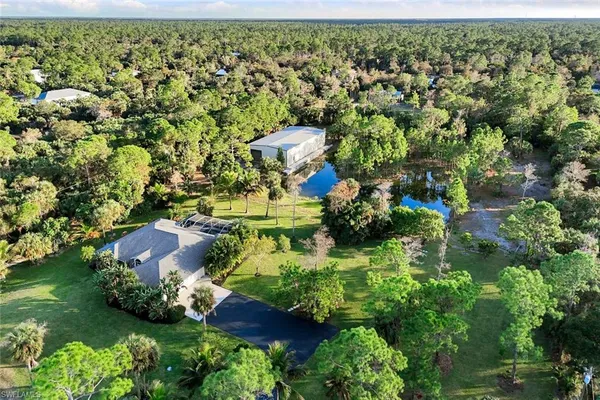 an aerial view of residential house with outdoor space and trees all around
