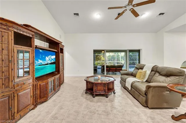 a living room with furniture a flat screen tv and floor to ceiling window
