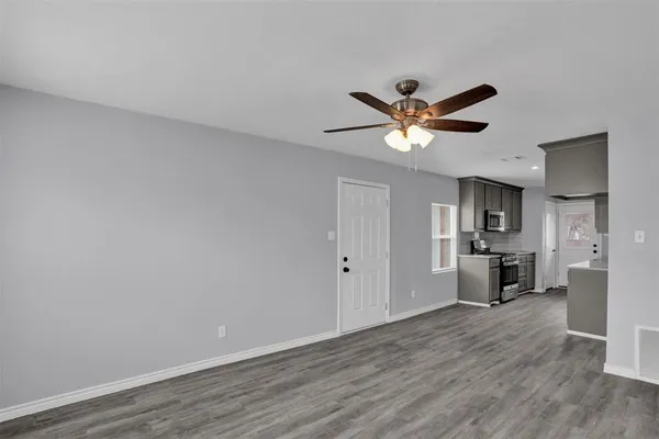 a view of an empty room with kitchen and a window