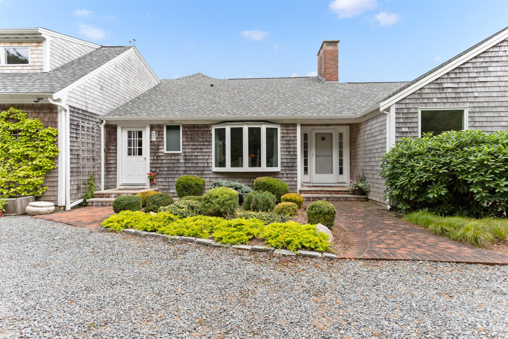 a front view of a house with a yard and potted plants