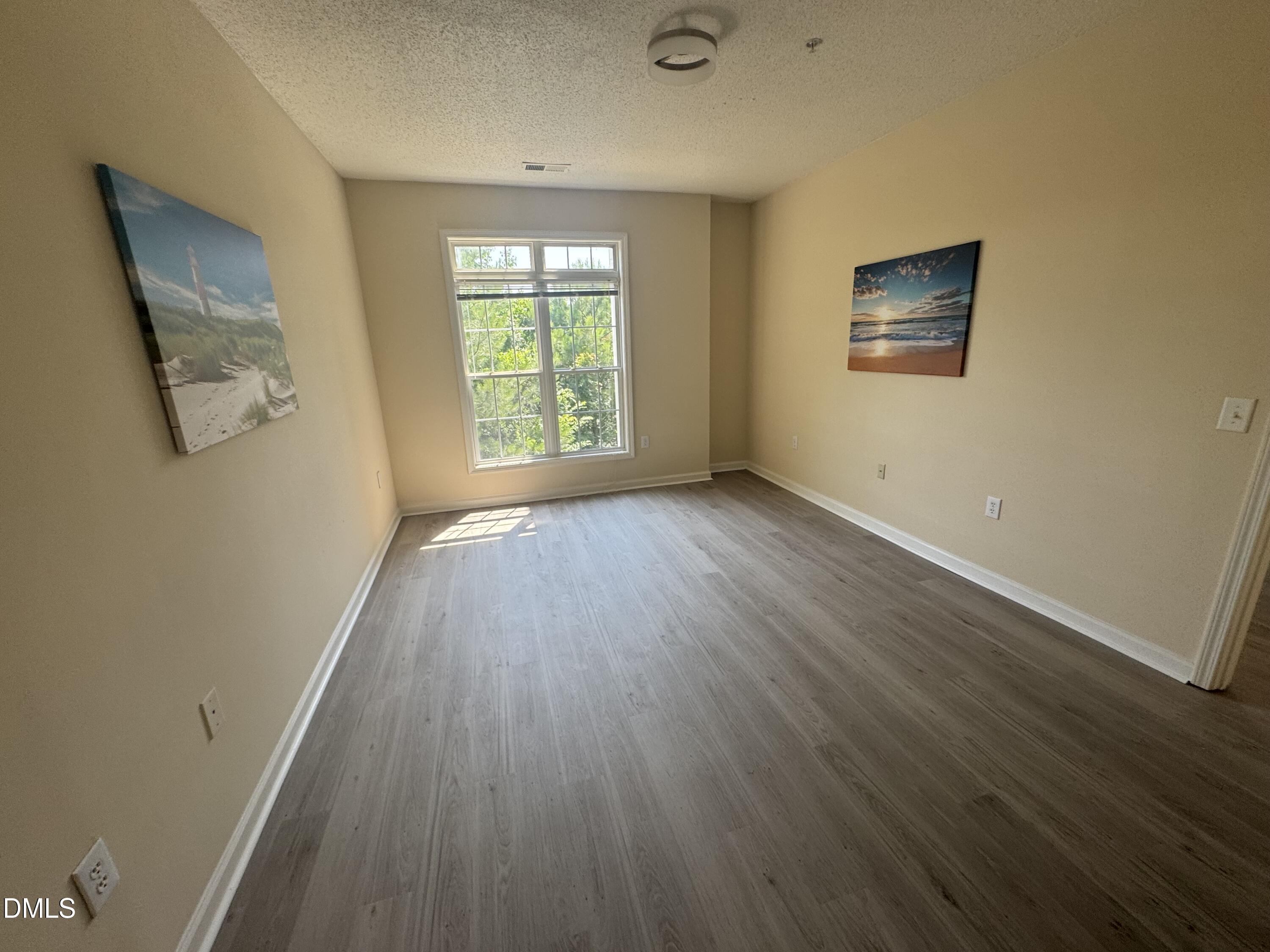 2520 Friedland Place, Unit 202 Raleigh, NC 27617 - Photo 9 of 14 a view of an empty room with wooden floor and a window