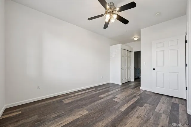 an empty room with wooden floor ceiling fan and a ceiling fan