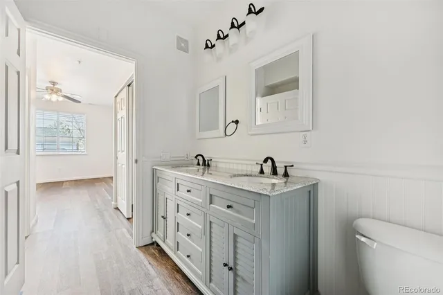 a bathroom with a granite countertop sink vanity mirror and toilet