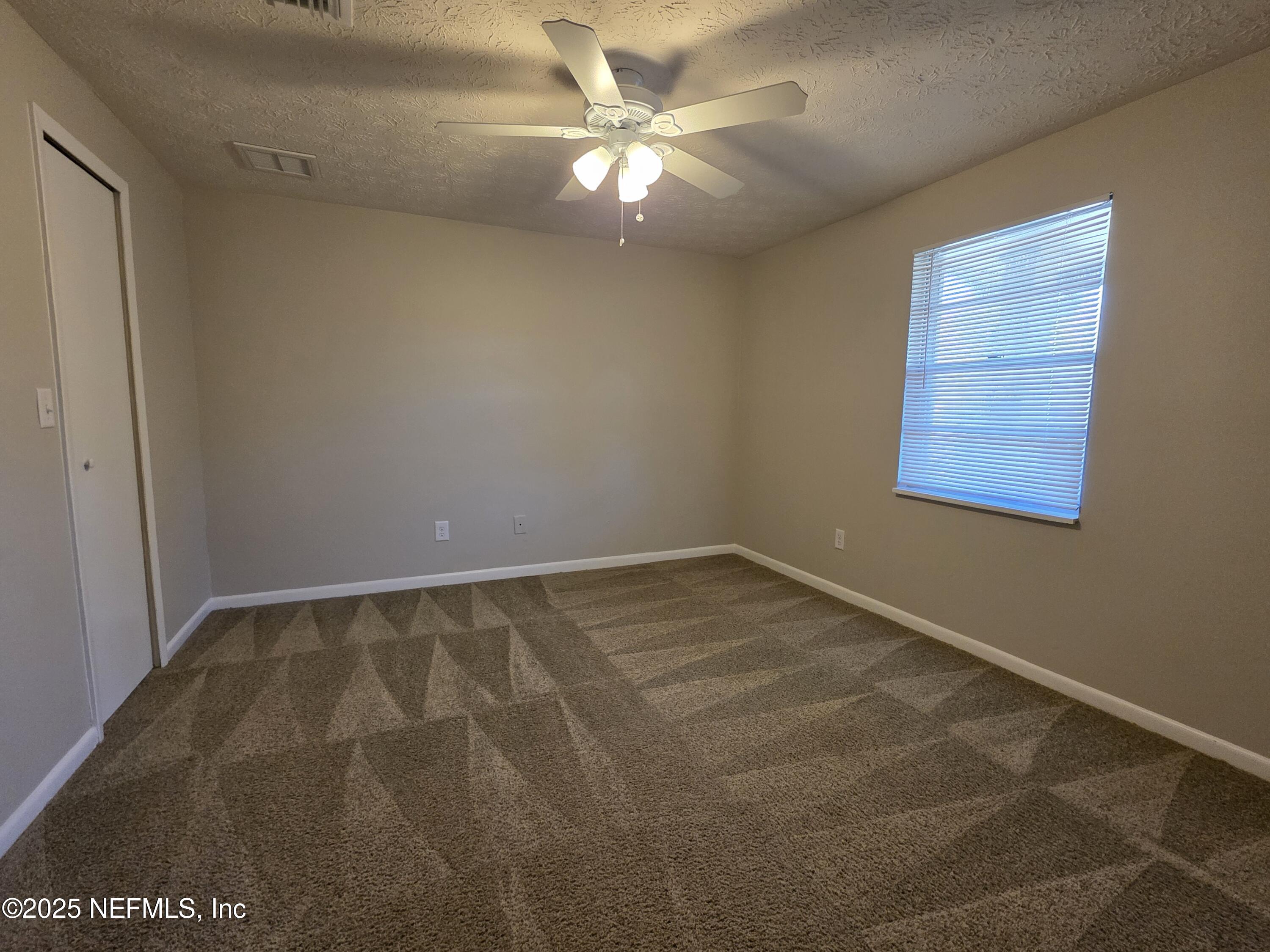 1143 Tumbleweed Drive Orange Park, FL 32065 - Photo 12 of 15 an empty room with a chandelier fan and windows