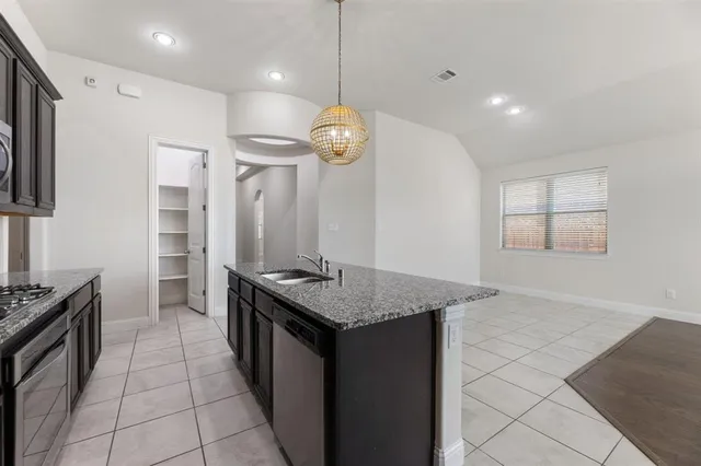 a kitchen with stainless steel appliances granite countertop a stove a sink and a microwave