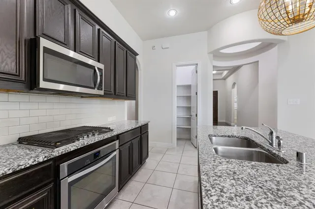 a kitchen with granite countertop a sink a stove top oven and cabinets