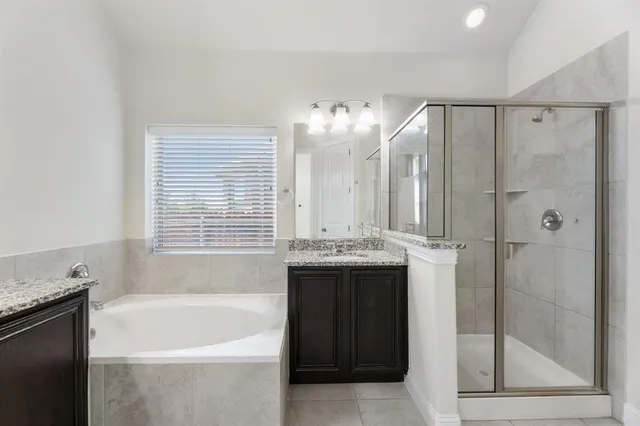 a bathroom with a granite countertop bathtub a double vanity sink and a mirror