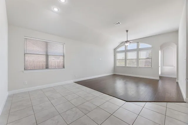 an empty room with wooden floor ceiling fan and window