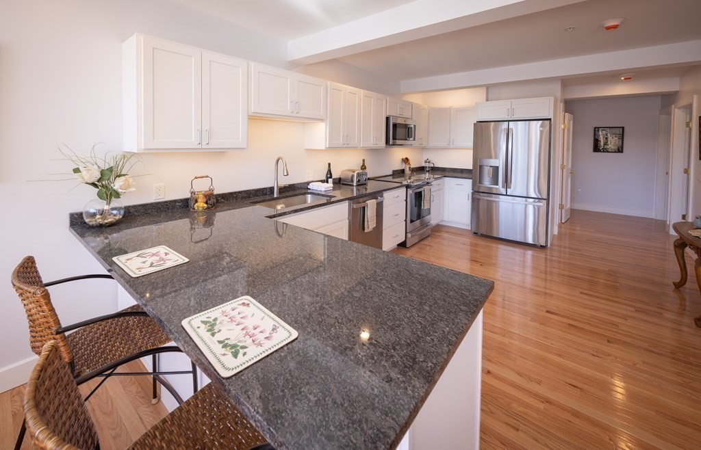 10 Deerfield Avenue, Unit 5 Shelburne, MA 01370 - Photo 12 of 28 a kitchen with stainless steel appliances granite countertop a refrigerator a stove a sink a dining table and chairs with wooden floor
