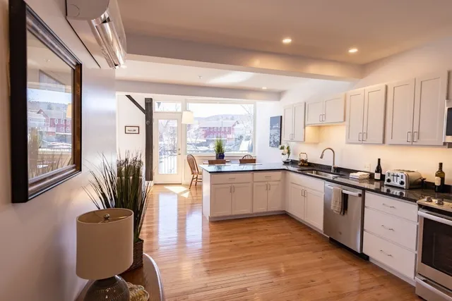 a kitchen with stainless steel appliances granite countertop a stove top oven a sink a dining table and chairs