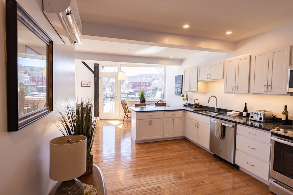 10 Deerfield Avenue, Unit 5 Shelburne, MA 01370 - Photo 13 of 28 a kitchen with stainless steel appliances granite countertop a stove top oven a sink a dining table and chairs