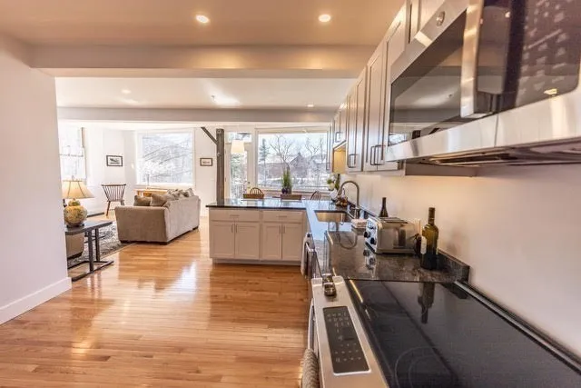 a living room with couches and kitchen view with wooden floor