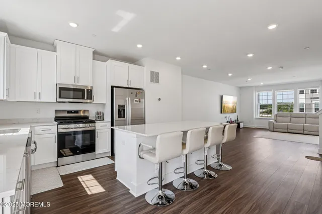 a large kitchen with stainless steel appliances refrigerator stove microwave and cabinets