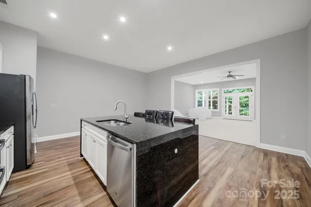a kitchen that has a sink and a stove with wooden floor