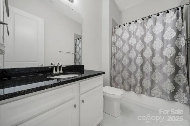 a bathroom with a granite countertop sink a toilet and a shower curtain