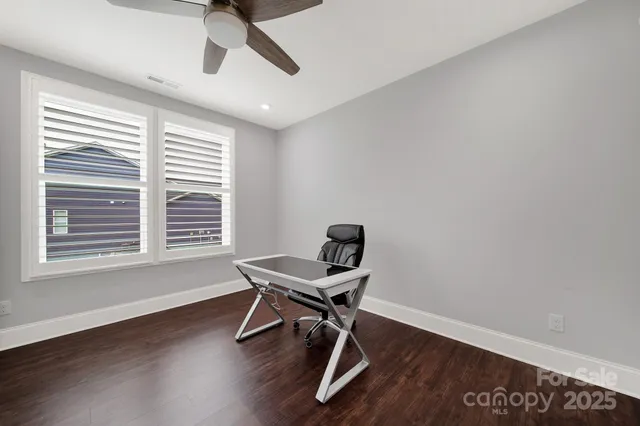 a room with wooden floor a ceiling fan and windows