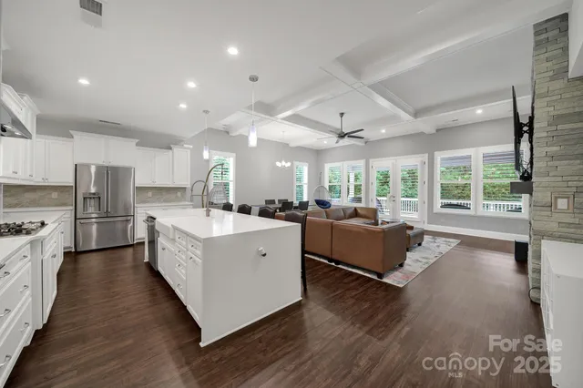 a large white kitchen with wooden floors and stainless steel appliances