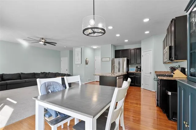 a kitchen with stainless steel appliances granite countertop a stove refrigerator and couches with wooden floor