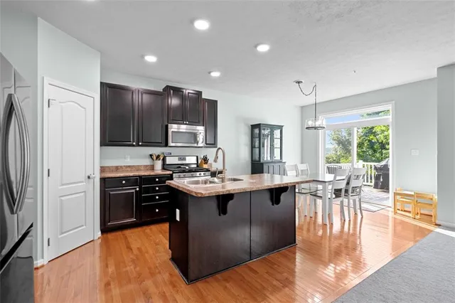 a kitchen with stainless steel appliances granite countertop a stove top oven a sink dishwasher a dining table and chairs with wooden floor