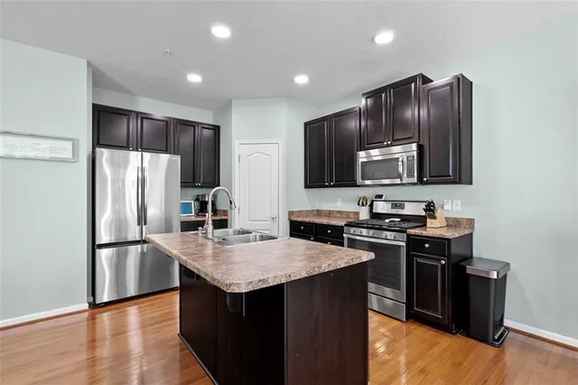 a kitchen with kitchen island granite countertop stainless steel appliances and wooden cabinets