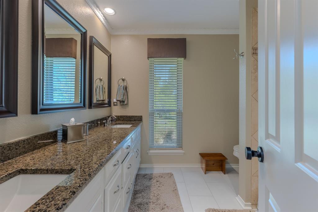 166 County Road 2112 Pittsburg, TX 75686 - Photo 19 of 40 a bathroom with a granite countertop double vanity sink a mirror and a bathtub