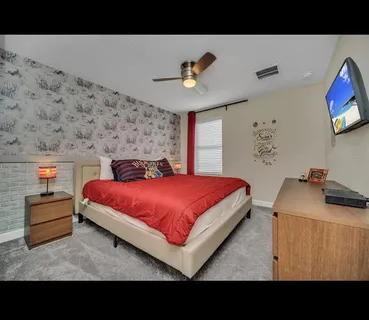 a bedroom with a bed and a flat tv screen on dresser