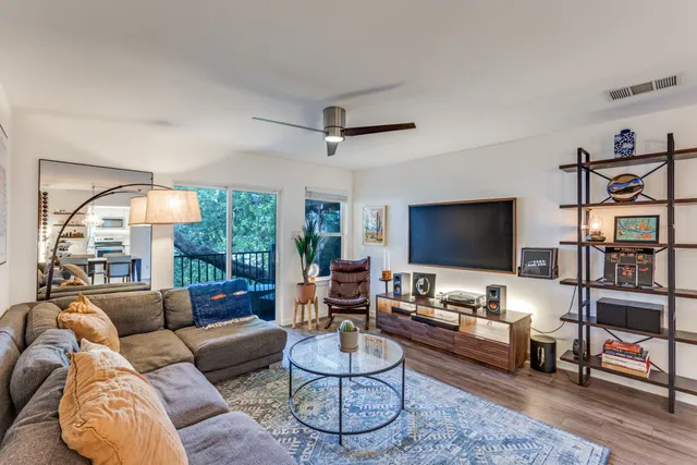a living room with furniture a flat screen tv and a large window