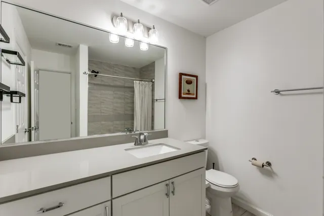 a bathroom with a toilet sink double vanity and mirror