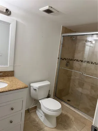 a bathroom with a granite countertop sink toilet and shower