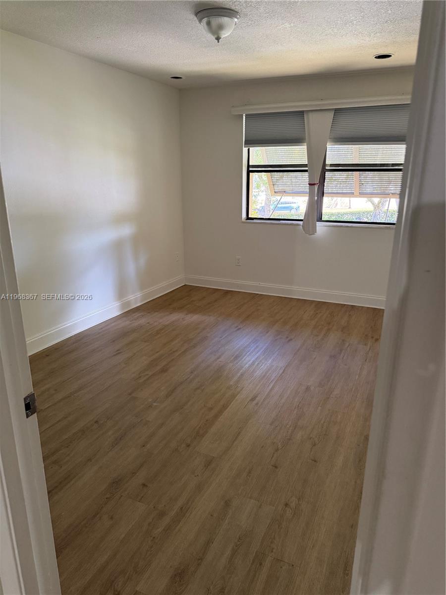 7925 Southwest 86th Street, Unit 923 Miami, FL 33143 - Photo 6 of 10 an empty room with wooden floor and windows
