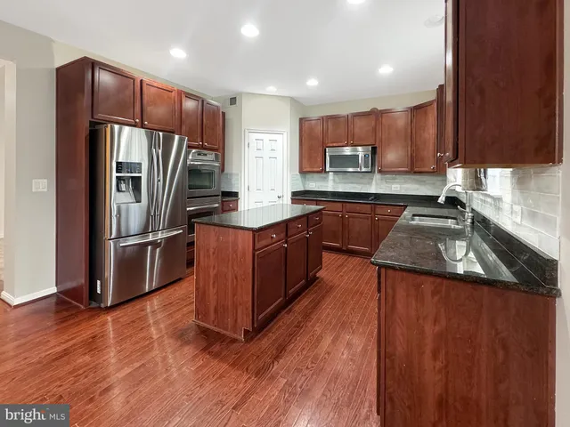 a kitchen with granite countertop a sink a stove and cabinets