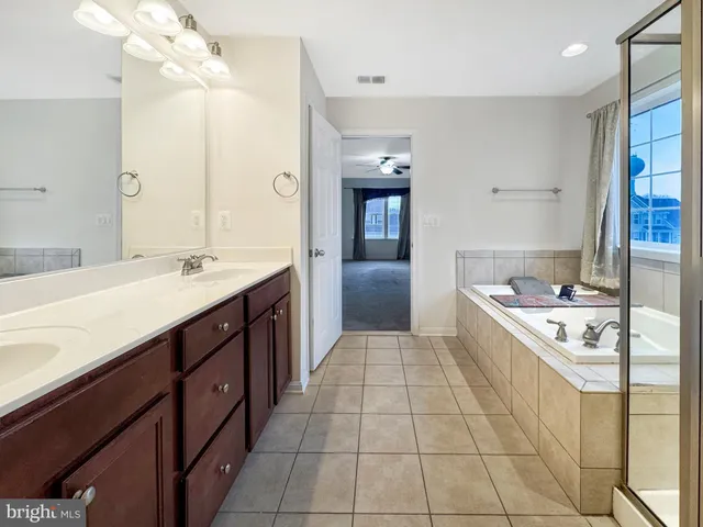 a spacious bathroom with a granite countertop sink a mirror and a bathtub