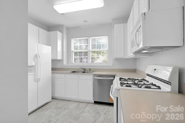 a kitchen with white cabinets and white appliances