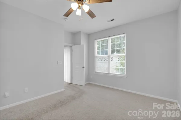 an empty room with a window and a fan