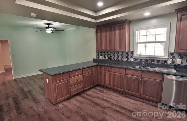 a kitchen with stainless steel appliances granite countertop a sink cabinets and wooden floor
