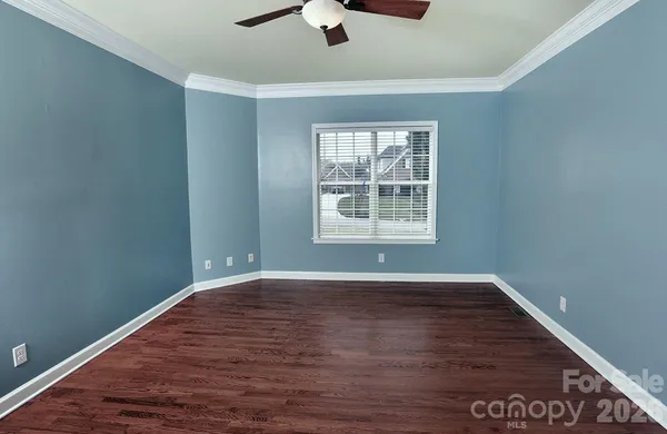 an empty room with wooden floor cabinet and windows