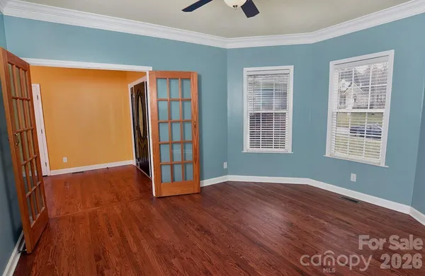 an empty room with wooden floor and windows