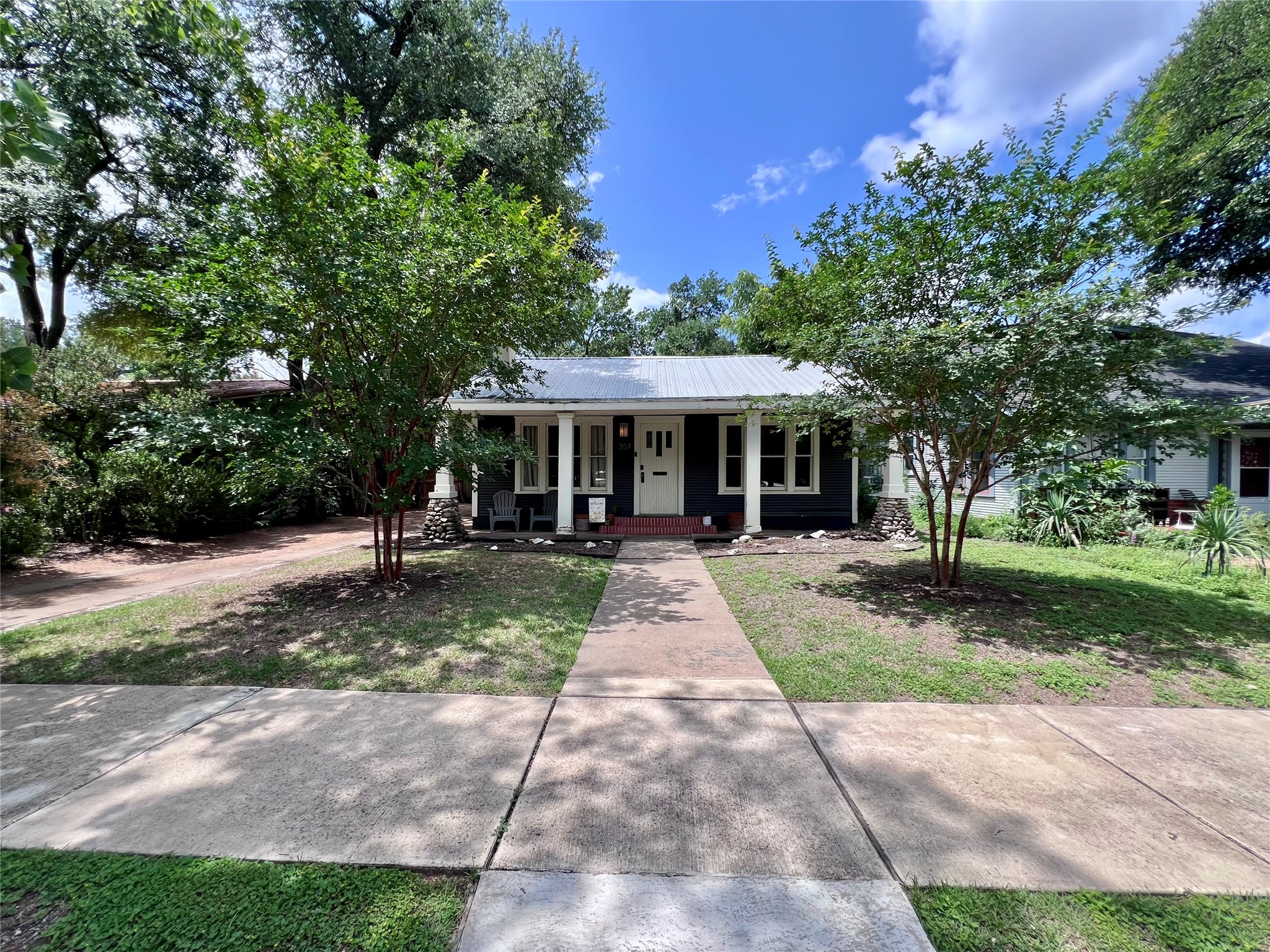 307 East 35th Street, Unit A Austin, TX 78705 - Photo 2 of 31 An inviting path leads to a welcoming home, framed by lush trees and a manicured yard.