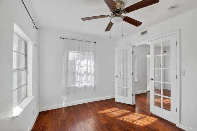 a view of an empty room with window and wooden floor
