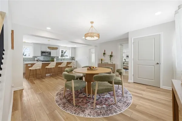 a dining room with wooden floor a chandelier a wooden table and chairs
