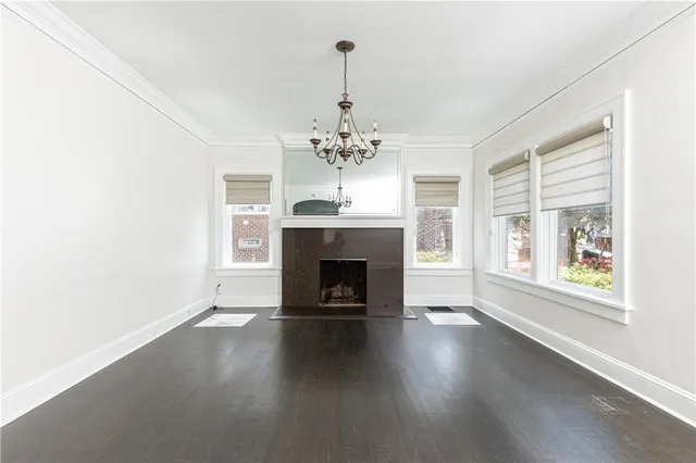 an empty room with wooden floor fireplace and windows