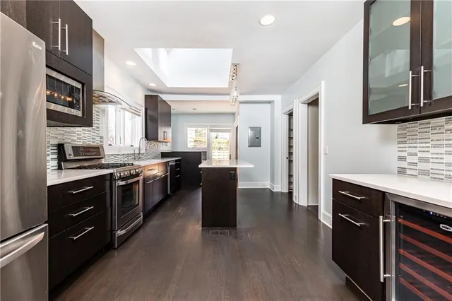 a kitchen with stainless steel appliances granite countertop a refrigerator a sink dishwasher a stove and white cabinets with wooden floor